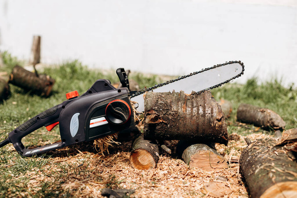 Chainsaw close up. Chainsaw with a tool. Chainsaw on the background of firewood - Photo, Image