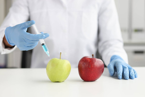 Scienziato in camice bianco facendo iniezione in mela verde in laboratorio - Foto, immagini