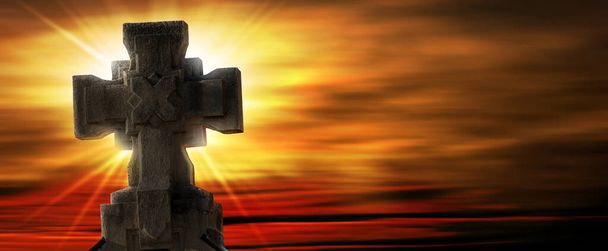 Primer plano de una antigua cruz religiosa de piedra contra un hermoso cielo al atardecer con rayos de sol y espacio para copiar. - Foto, imagen