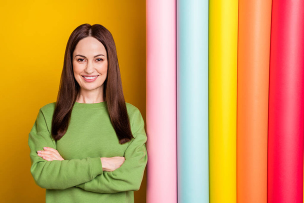 Portrait of attractive cheerful woman folded arms choosing paint colorful variant isolated over bright yellow color background - Photo, image