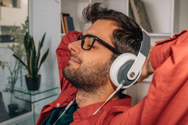 розслаблений чоловік вдома слухає музику з навушниками
 - Фото, зображення