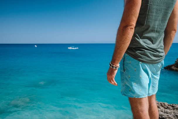 Close up of a tourist man aganist blue Ionian sea at Lefkada Island, Greece. - 写真・画像