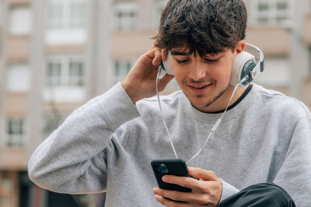 Teenager mit Kopfhörer und Handy in der Stadt - Foto, Bild