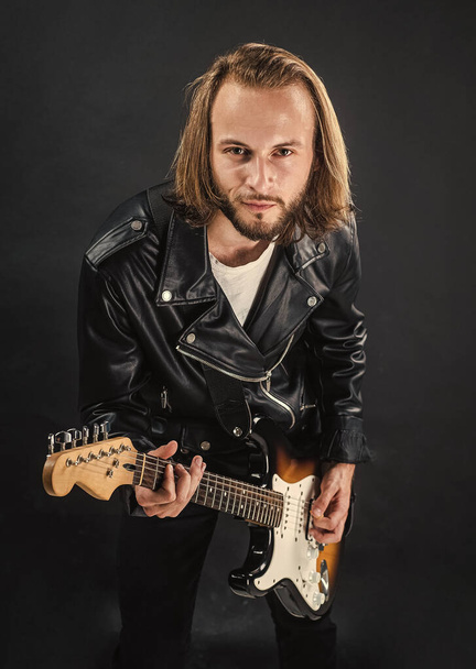 bearded rock musician playing electric guitar in leather jacket, electric bass - Fotó, kép
