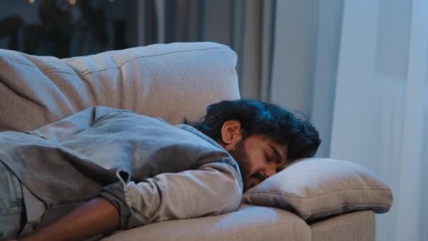 Εξαντλημένο σύνδρομο κακό συναίσθημα κουρασμένος αραβικός άνθρωπος ινδική γενειοφόρος εργάτης αρσενικό στο σπίτι πέφτει κάτω πρόσωπο στον καναπέ καναπέ αργά το βράδυ σκοτεινό υπερφορτωμένο άρρωστο άτομο έλλειψη ενέργειας μετά το κόμμα - Πλάνα, βίντεο