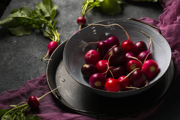 Round multi-colored radish in a gray bowl on a dark background - Photo, Image