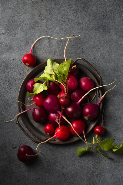 Round multi-colored radish on an old tray on a dark background - 写真・画像