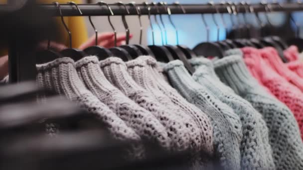 Detailní oblečení věšák s barevnými svetry v oděvnictví obchod ženské ruce třídění oblečení nepoznatelná žena zákazník si vybere oblečení v butiku nakupuje nové věci nákupy sleva nákup prodej - Záběry, video