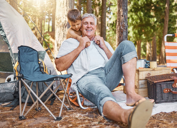 Kempingezni nagyapával. Teljes hosszúságú felvétel egy jóképű, érett férfiról és az unokájáról, amint az erdőben ülnek a táborhelyükön.. - Fotó, kép