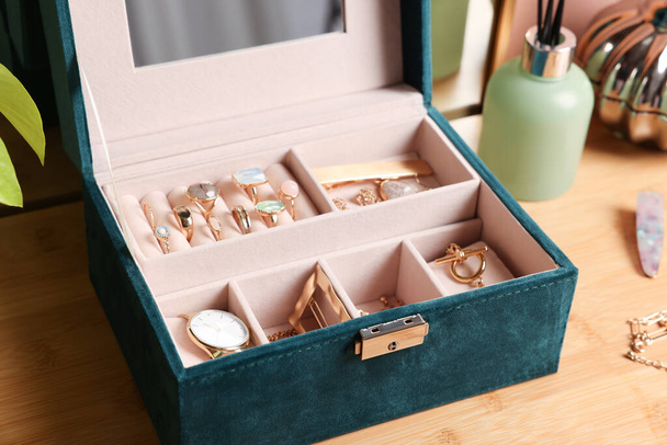 Elegant jewelry box with beautiful bijouterie and expensive wristwatch on wooden table, closeup - Foto, imagen