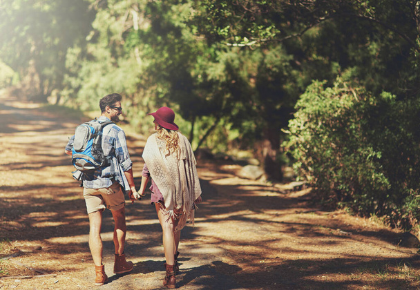 Zu Fuß in die Wildnis. Rückansicht eines liebevollen jungen Paares während einer Wanderung. - Foto, Bild