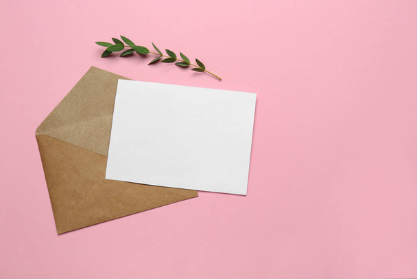 Brown envelope with blank letter and plant on pink background, flat lay. Space for text - Photo, Image