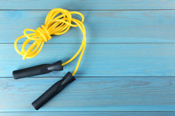 Skipping rope on light blue wooden table, top view. Space for text - 写真・画像