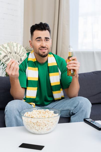 disappointed sports fan with money and beer watching match at home - 写真・画像
