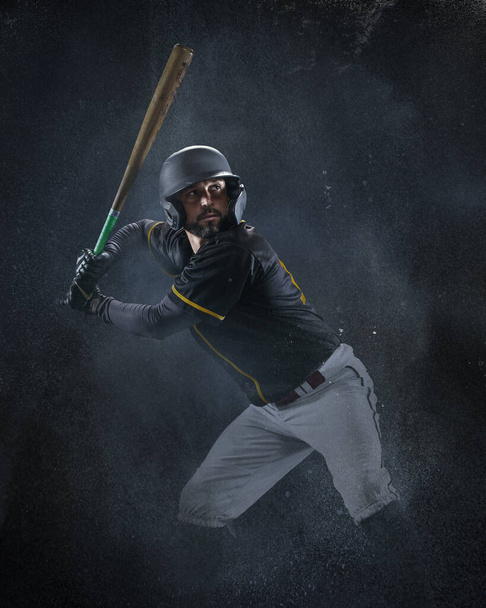 Creative portrait of professional baseball player in sports equipment getting ready to hit isolated on smoked background. Sport, art, action, hobby concept - Foto, afbeelding