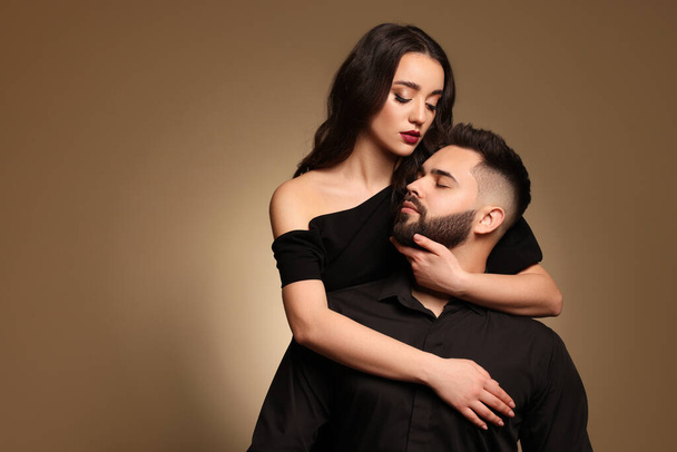 Handsome bearded man with sexy lady on light brown background. Space for text - Fotó, kép