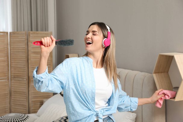 Woman in headphones with hairbrush singing at home - Fotoğraf, Görsel