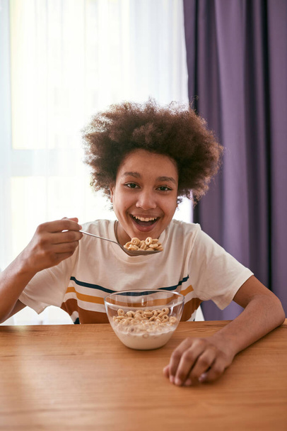 Front view of black boy eating cereals at table - Photo, Image