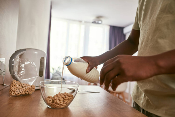 Black man pouring milk in bowl with cereals - Fotoğraf, Görsel