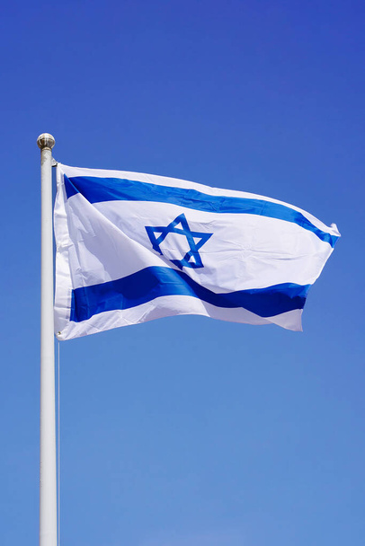 Izrael zászlója integet a tiszta kék ég ellen, közelről. Izrael zászlója a kék égen. Térkép Israel on blue sky background - Fotó, kép