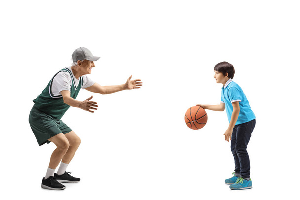 Full length profile shot of a boy playing basketball with an elderly man isolated on white background - Fotografie, Obrázek