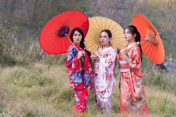 女の子はどこへ行くでしょう。着物と桜の花を着た魅力的なアジアの女性。アジアの美容スキンケア女性側で見て. - 写真・画像