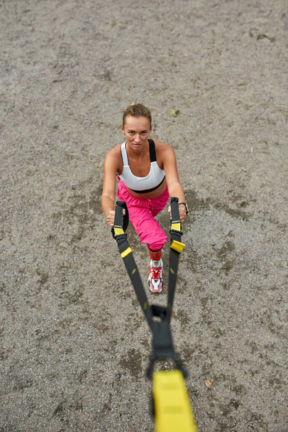 Disabled athletic girl doing sit ups with belts - Foto, afbeelding