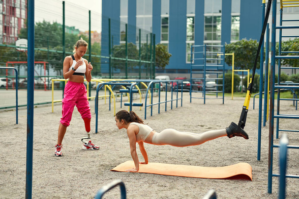 Disabled girl with friend taining on sports ground - Foto, Imagen