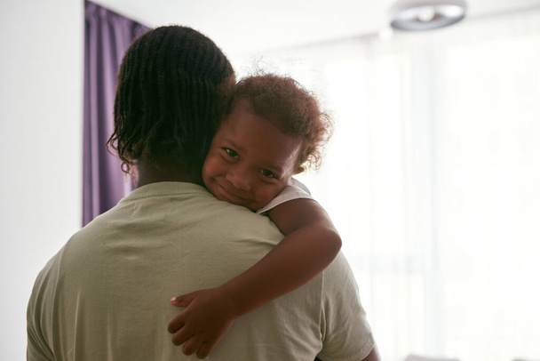 negro padre hold y abrazo sonriente hija en brazos - Foto, imagen