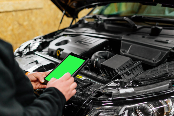 Auto monteur met tablet doet diagnostiek detecteren storing. Moderne auto rapair winkel - Foto, afbeelding
