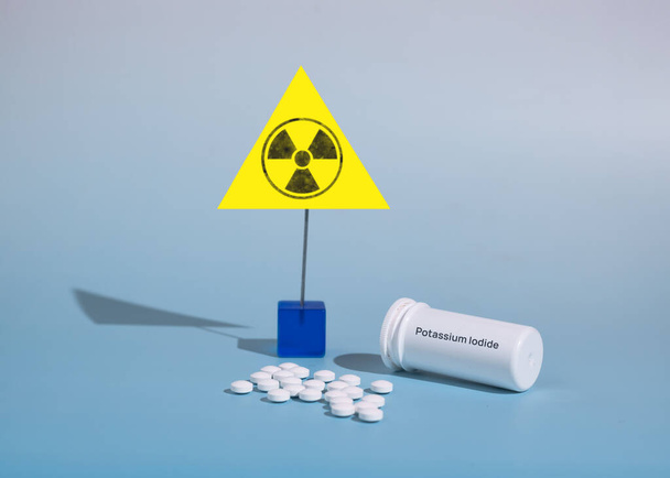 Kaliumjodide tabletten voor gebruik in geval van radioactieve besmetting en stralingsverschijnselen op een blauwe achtergrond. De naam van het geneesmiddel staat op de doos. Vooraanzicht. - Foto, afbeelding