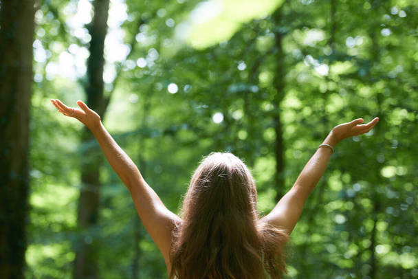 Enjoying the forest. Rearview of a beautiful young woman with her arms raised while standing in a forest. - Foto, imagen