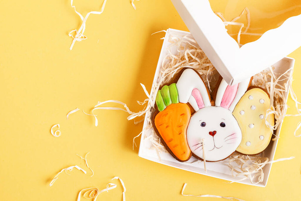 Gingerbread cookie in the shape of rabbit head with carrot and egg. Easter bunny cookie in the gift box on the yellow background. - Foto, immagini