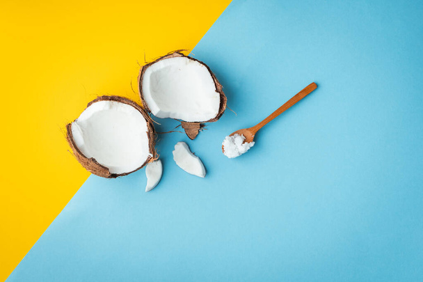 Cracked coconut with pieces on the yellow and blue background - Photo, Image