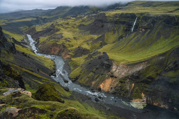 青い水の流れと緑の丘や苔で覆われた崖と高地の谷や川フォッサのアイスランドの風景。南アイスランド. - 写真・画像