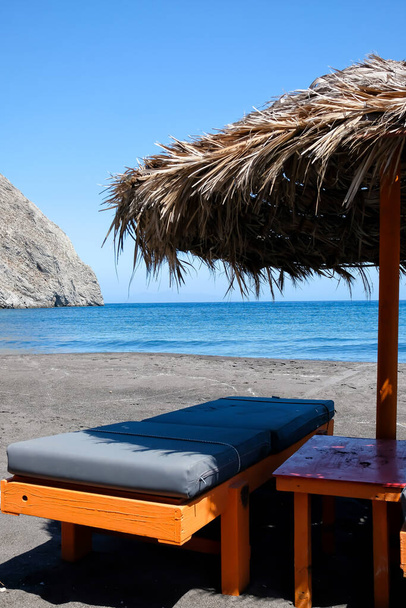 Leere Liegestühle und Sonnenschirme am berühmten Sandstrand von Perissa auf Santorin - Foto, Bild