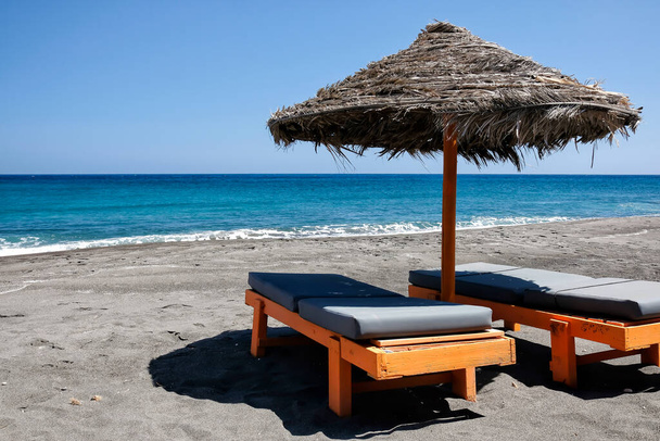 Tyhjät aurinkotuolit ja aurinkovarjot kuuluisalla Perissan hiekkarannalla Santorinissa - Valokuva, kuva