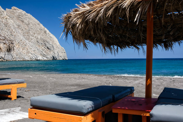 Пустые шезлонги и зонтики на знаменитом песчаном пляже Перисса в Санторини - Фото, изображение