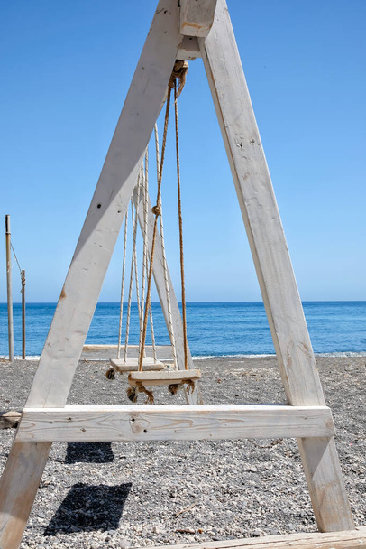 Вигляд дерев "яного гойдалки на піщаному чорному пляжі Перісса у Санторіні. - Фото, зображення