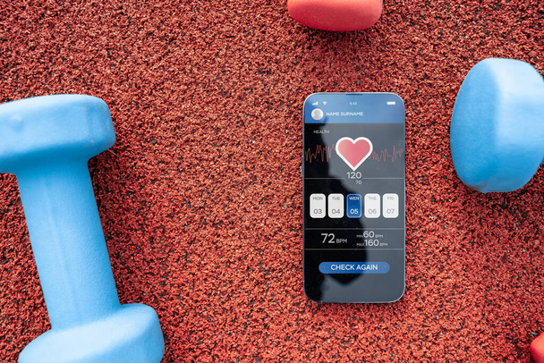 Domanda di palestra. Schermo smart phone con fitness salute o palestra sportiva applicazione mobile su sfondo manubrio. Programma di fitness online - Foto, immagini