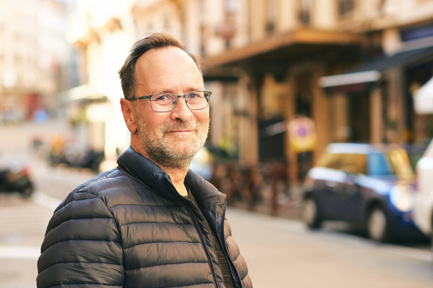 Portrait extérieur de l'homme d'âge moyen en ville, veste bleue et lunettes - Photo, image