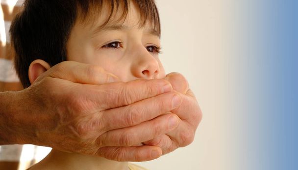 closeup rude male hands cover the mouth of a child, a boy suffers from violence, concept of parenting, punishment for bad words, children's jokes, teasing, ban on his opinion - Foto, Bild