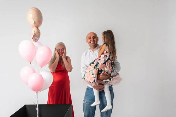 Schöne schwangere Frau mit Familie auf hellem Hintergrund, fröhlich, feiernd und überrascht.Konzept von Familie und Geburt - Foto, Bild