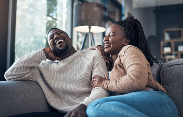 We never go a day without laughing. Cropped shot of a happy young couple sitting together and bonding during their weekend at home. - Fotografie, Obrázek