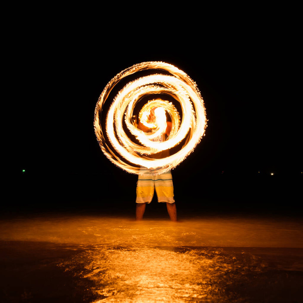 Fire poi in action on the beach at night - 写真・画像