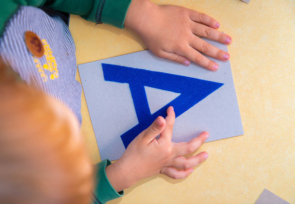 Die Hände eines Kindes europäischen Aussehens umkreisen den englischen Buchstaben A - Foto, Bild