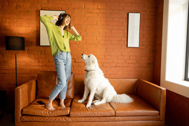 Γυναίκα διασκεδάζει με το σκύλο της σε έναν καναπέ στο σπίτι - Φωτογραφία, εικόνα