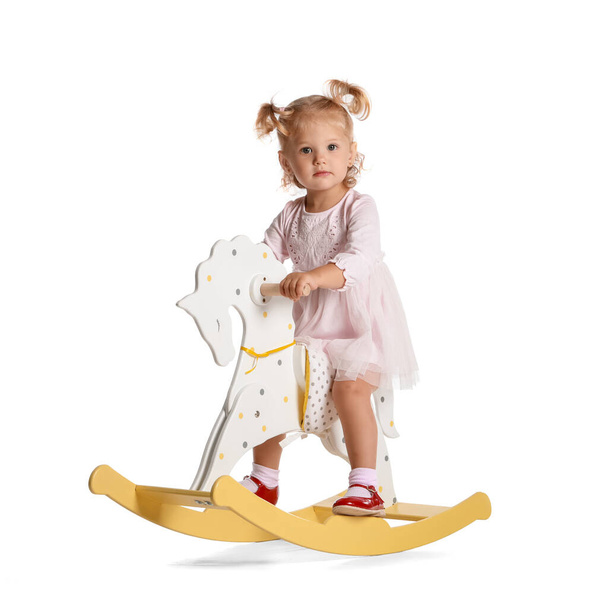 Adorable baby girl with rocking horse on white background - Photo, Image