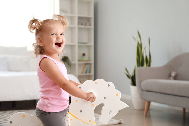 Adorable baby girl with rocking horse at home - Photo, Image