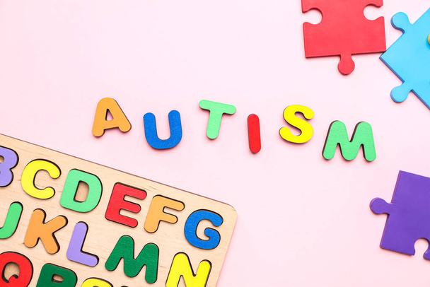 Word AUTISM with puzzle pieces and letters on pink background - Photo, Image